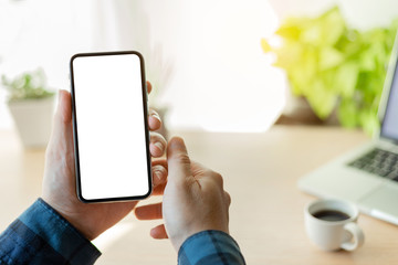 Mockup image blank white screen cell phone.man hand holding texting using mobile on desk at coffee shop.background empty space for advertise text.people contact marketing business,technology 