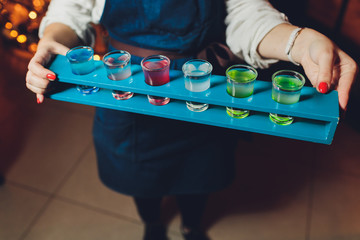 Waiter serving shots on a wooden tray.