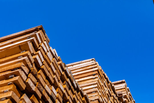 A low angle shot of a large pile of lumber boards stored in a sawmill yard. Woodworking and timber manufacture and supply industry, with copy space © Valmedia