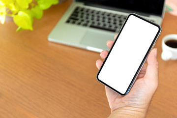 Mockup image blank white screen cell phone.man hand holding texting using mobile on desk at coffee shop.background empty space for advertise text.people contact marketing business,technology 