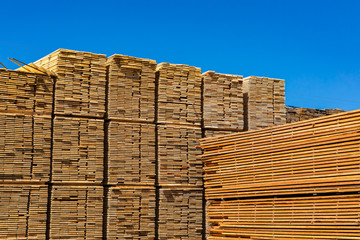 Large piles of sawn and processed wood boards are seen in a sawmill yard. Heavy industry in the Kootenays of British Columbia, Canada. With copy space - obrazy, fototapety, plakaty