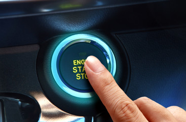 Finger pressing the start or stop engine button in close up.