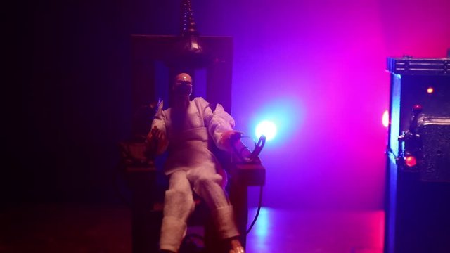 Death penalty electric chair miniature on dark. Creative artwork decoration. Image of an electric chair scale model on a dark backgorund