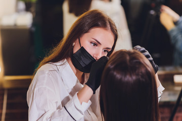 beautician- makeup artist applies paint henna on previously plucked, design, trimmed eyebrows in a...