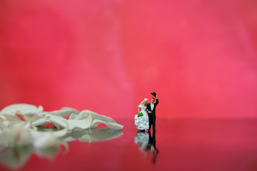 Miniature photography - garden flower / outdoor wedding concept, bride and groom walking on shiny floor with white rose petal