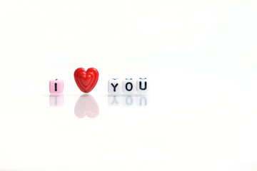 Miniature / toys photography for valentines day - i love you beads word block on shiny white background