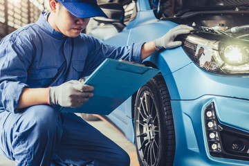 Asian car mechanic technician holding clipboard and checking to maintenance vehicle by customer...