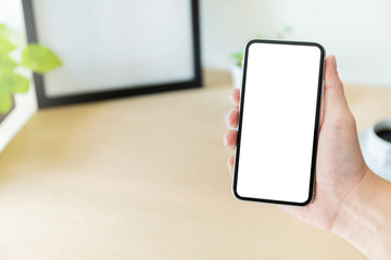 Mockup image blank white screen cell phone.man hand holding texting using mobile on desk at office.background empty space for advertise text.people contact marketing business,technology 
