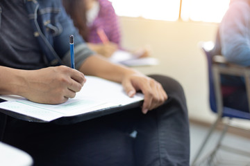 high school,university student study.hands holding pencil writing paper answer sheet.sitting lecture chair taking final exam attending in examination classroom.concept scholarship for education abroad