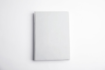 Book with blank cover on white background, top view