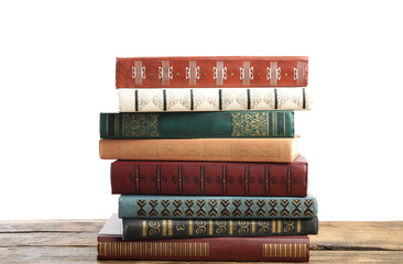 Stack of old vintage books on wooden table against white background
