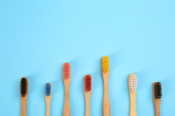 Toothbrushes made of bamboo on light blue background, flat lay. Space for text