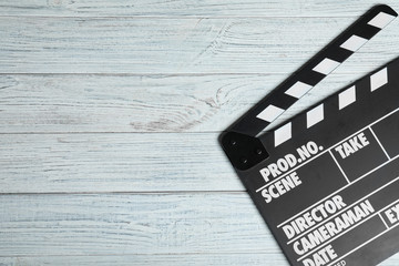 Clapperboard on white wooden table, top view with space for text. Cinema production