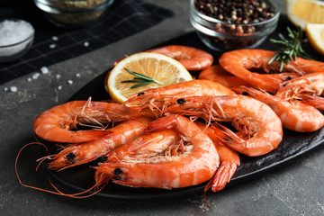 Delicious cooked shrimps with rosemary and lemon on dark grey table