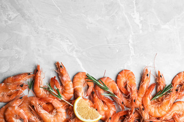 Delicious cooked shrimps with rosemary and lemon on grey marble table, flat lay. Space for text