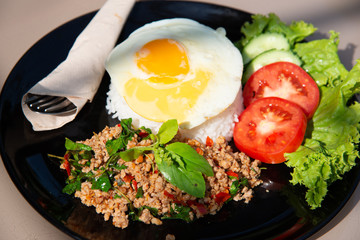 Stir fried basil with minced pork and fried egg, tomato in black dish