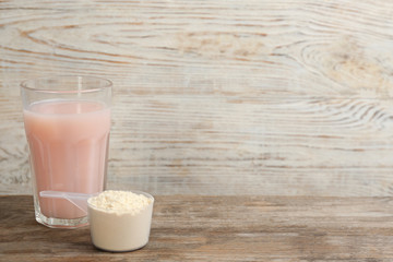 Protein shake and powder on wooden table, space for text