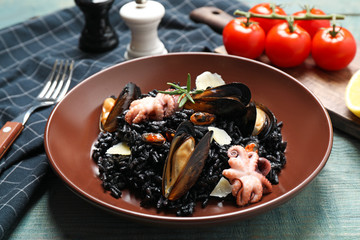 Delicious black risotto with seafood on blue wooden table, closeup