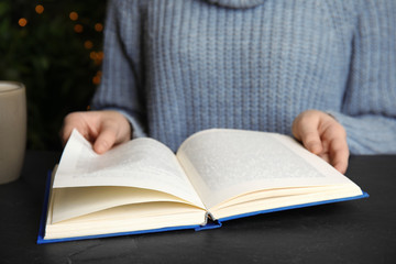 Young woman reading book at table, closeup