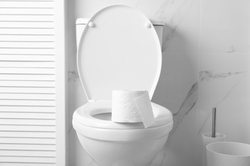 New paper roll on toilet bowl in bathroom