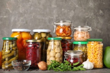 Fototapeta na wymiar Glass jars with different pickled vegetables on grey table