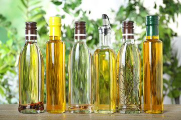 Different sorts of cooking oil in bottles on wooden table