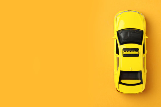 Yellow taxi car model on orange background, top view. Space for text