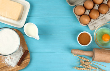 Flat lay composition with eggs and other ingredients on light blue wooden table, space for text. Baking pie