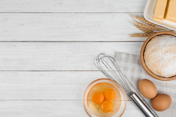 Flat lay composition with eggs and other ingredients  on white wooden table, space for text. Baking pie
