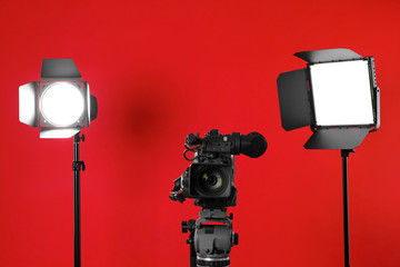 Professional video camera and lighting equipment on red background
