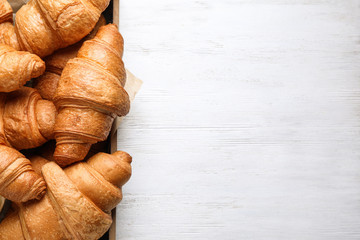 Tasty fresh croissants on white wooden table, top view. Space for text