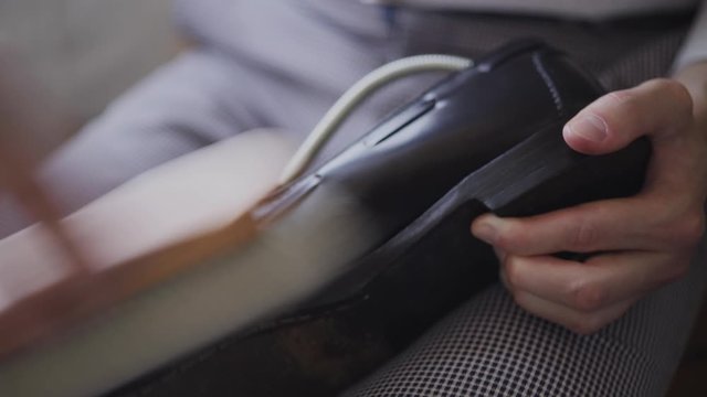 Close-up of a young Caucasian man repairing an old male leather shoe.