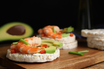 Puffed rice cakes with shrimps and avocado on wooden board, closeup