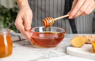 Woman with tasty honey at marble table, closeup