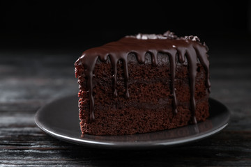 Delicious chocolate cake on black wooden table, closeup