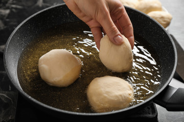 Woman cooking delicious donuts in oil, closeup