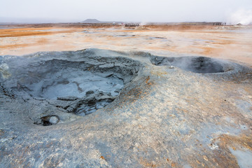 Bubbling geothermal hot/mud pool in the Hverarond area near Myvatn in the Icelandic landscape. Colorful and textured volcanic mineral rich sulphur ground infront.