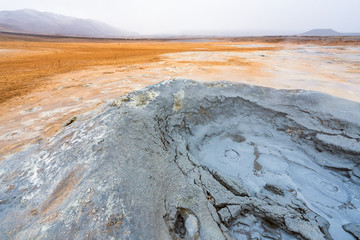 Bubbling geothermal hot/mud pool in the Hverarond area near Myvatn in the Icelandic landscape. Colorful and textured volcanic mineral rich sulphur ground infront.