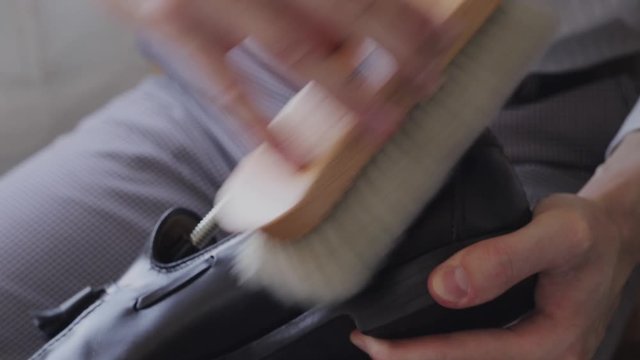 Close-up of a young Caucasian man repairing an old male leather shoe.