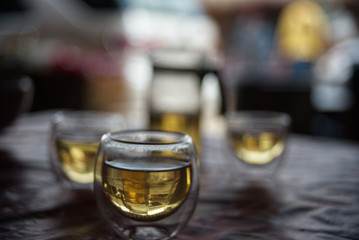 An oval transparent tea glass cup with blur tea set background