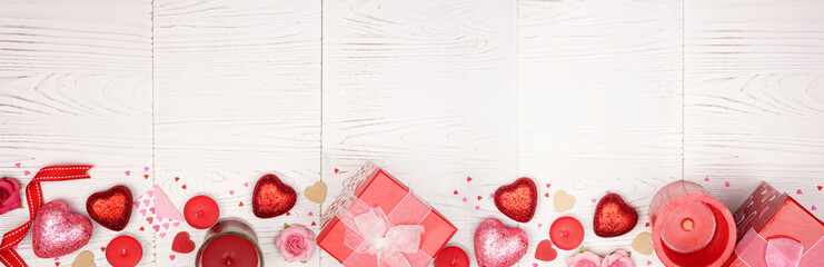 Valentines Day long banner border with red gifts and decorations. Top view over a rustic white wood background. Copy space.