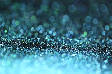 Blue glitter with green bokeh on a black background. Turquoise glitter brilliant mockup.Vibrant background with twinkle lights.blue shiny  layout.