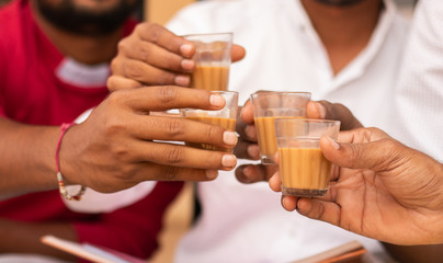 Close up of hands cheers Tea glasses - concept showing group of friends enjoying morning Tea by...