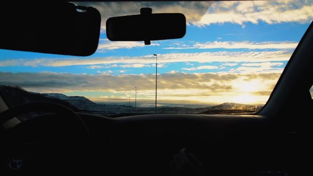 Shot from a moving car of iceland westfjords with mountains and hills, during a cloudy sunset