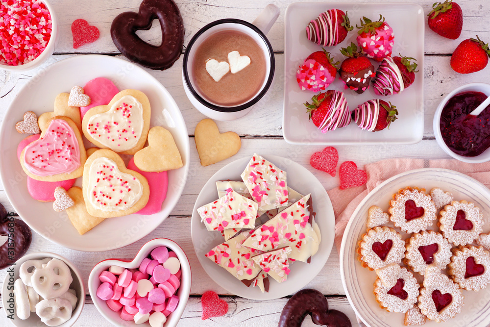 Poster valentines day table scene with a selection of sweets and cookies. top view over a white wood backgr