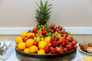 Fresh ripe fruit plate with grapes, strawberry, tangerines, pineapple