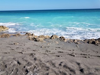 rocks and sand on shore at Florida beach with ocean and waves