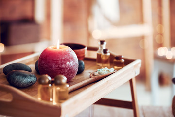 Tray with glowing candle and spa supplies in beauty salon