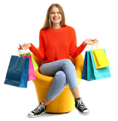 Beautiful woman with shopping bags sitting in armchair on white background