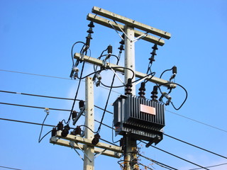Three-phase electrical transformers and cables on poles On the background and lines along the...